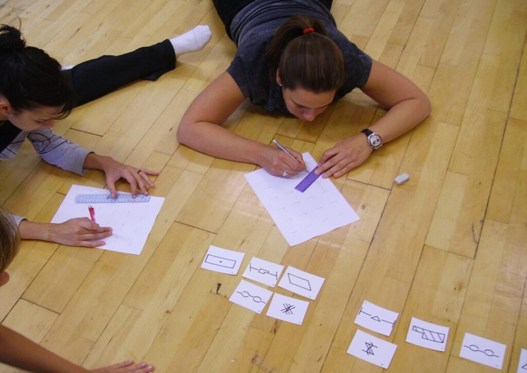Adult students looking at symbols' flashcards and writing on notepads
