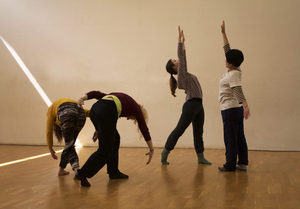 Four adults in a dance studio holding different poses