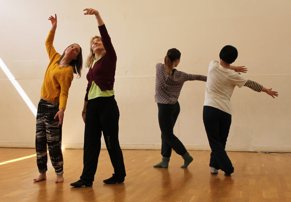 Two pairs of adults in a dance studio, each pair holding a different pose